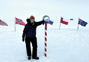Grace Cordsen ’19 stands next to a pole in a circle of flags standing in the snow.