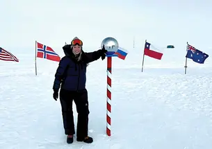 Grace Cordsen ’19 stands next to a pole in a circle of flags standing in the snow.