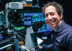 Michael B. Elowitz *99 with a microscope.