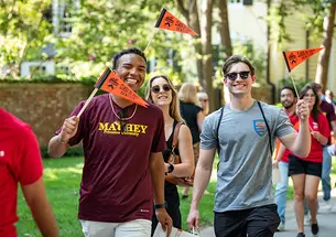 Waving orange pennants, students march in the 2023 Pre-rade.