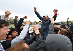 Cheering students hoist Fred Samara onto their shoulders; he holds up two fists to signal victory. 