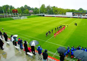 Women’s soccer players walk onto the field in two lines before the start of the game.