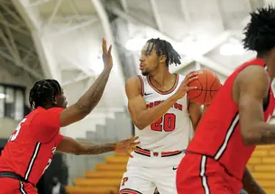 This is a photo of Tosan Evbuomwan ’23 playing against Marist in November. He's holding the ball to his left and looking right while another player tries to block him.