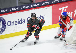 Two hockey players skate around the back of the goal.
