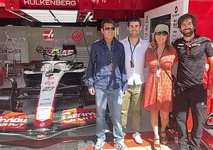 Stefano Chiazza *13 and three other people stand in a garage with a Formula 1 racecar.