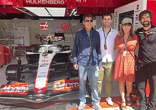 Stefano Chiazza *13 and three other people stand in a garage with a Formula 1 racecar.