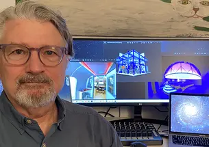 This is a photo of Dave Pentecost in front of the computer screens where he's working on the planetarium.