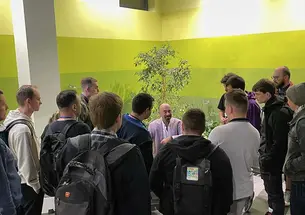 David Spergel ’82 talks to a room full of young men. A small tree is behind him and the walls are shades of green.