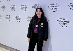 Diana Chao stands in front of a wall printed with the logo for this year's World Economic Forum.