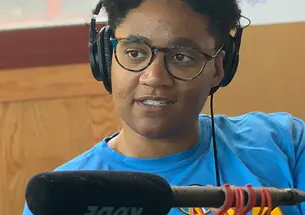 Erisa Apantaku ’14 wearing headphones in front of a microphone.