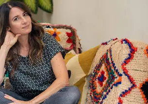 This is a photo of Julia Storm ’96 sitting on a couch with a couple of crocheted blankets on it.