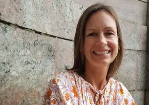 This is a headshot photo of Lara Bergen ’90 with a stone wall in the background.