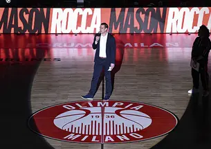 Mason Rocca ’00 stands in a spotlight on a basketball court that reads "Olimpia Milano."