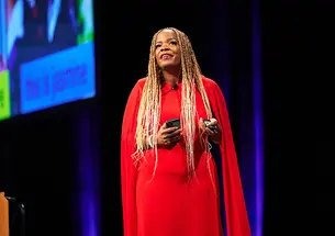 Michelle Silverthorn ’04 speaks on a stage, with a large screen behind her.