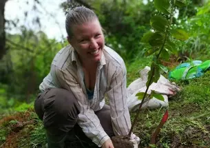 Ruth Metzel smiles as she lowers a plant into the ground.