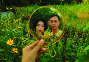 Two people in a field, reflected in a round mirror.