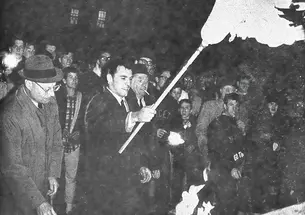 All-American Cosmo Iacavazzi ’65 *68 lights the bonfire, with coach Dick Colman (in glasses) by his side.