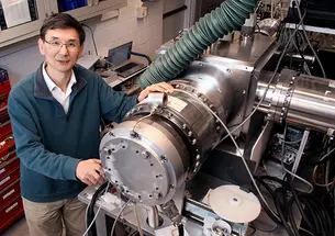 Yiguang Ju and some sort of machine with a red tool chest in the background.