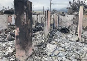 Miles Patrie’s house after the fire; in between charred cinderblock walls and posts are ash and burned building materials on the ground.
