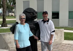 Two people stand with a statue.