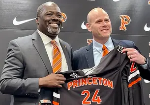 Athletics director John Mack ’00, left, and men’s hockey coach Ben Syer, right hold a Princeton hockey jersey at an April 26 press conference. 