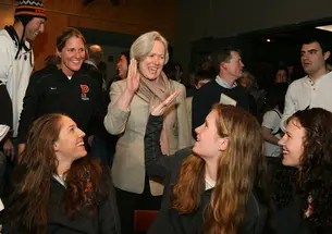 President Tilghman high-fives guard Blake Dietrick '15 as the Tigers await their destination at a March 18 selection-show party in Princeton. Princeton earned a No. 9 seed, facing No. 8 Florida State in the opening round.