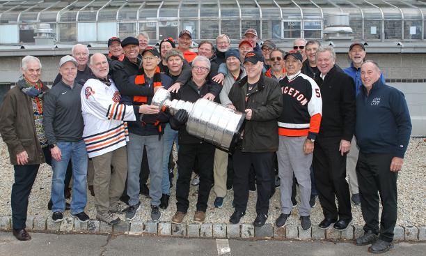 A crowd of about 20 alumni gather around the Stanley Cup. Gen. Mark Milley ’80, is front row, fourth from right.