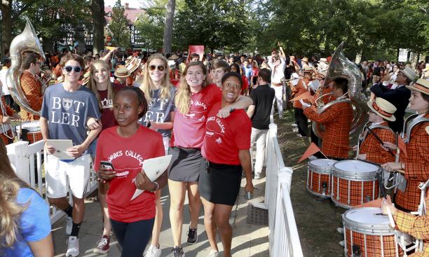 Students walking in the Pre-rade in on the front campus with band members alongside the path
