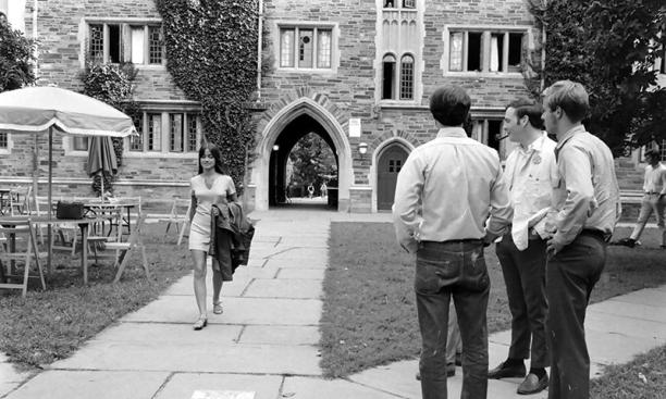 An undergraduate woman walking past three male students