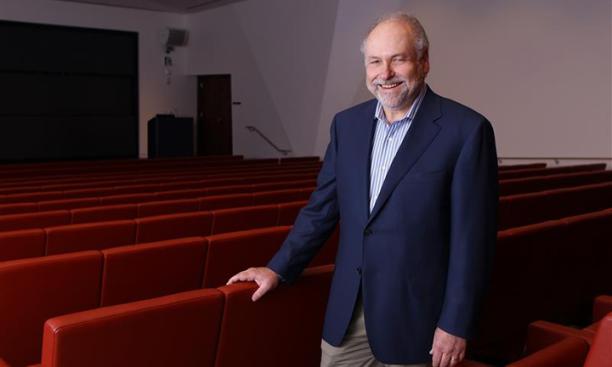 Pablo Debenedetti stands in a theater, his hand on the back of a red seat.