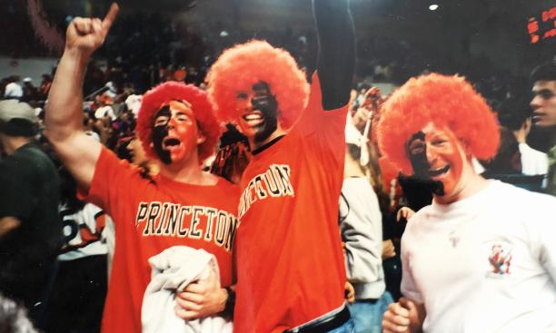 Wearing a puffy orange wig and orange-and-black face paint, Grant Wahl ’96, center, cheers for Princeton at a men’s basketball game.