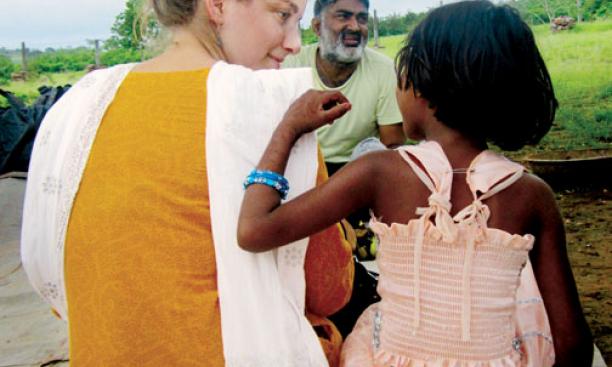Shaina Watrous ’14, director of a documentary about Ajeet Singh, center, listens to a child in Varanasi, India.