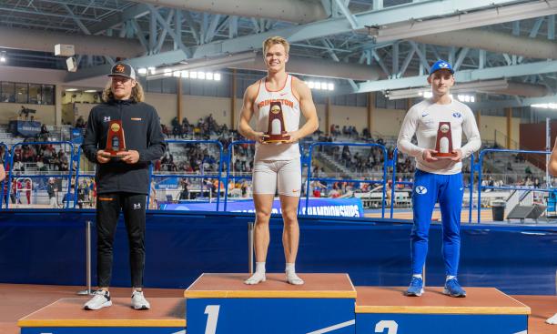 This is a photo of three pole vaulters holding trophies on the podium; Sondre Guttormsen ’23 stands highest in the center.
