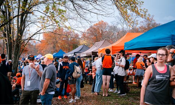 The photo shows spectators amid a line of tents at the 150th anniversary celebration for Princeton Rowing.