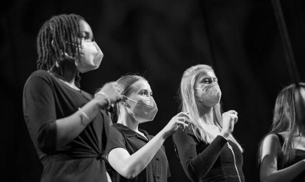 This is a black-and-white photo of four Tigerlilies performing wearing masks during the Princeton Sing-Off.