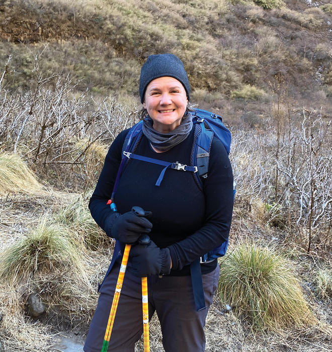 A woman smiles outdoors on a hike.