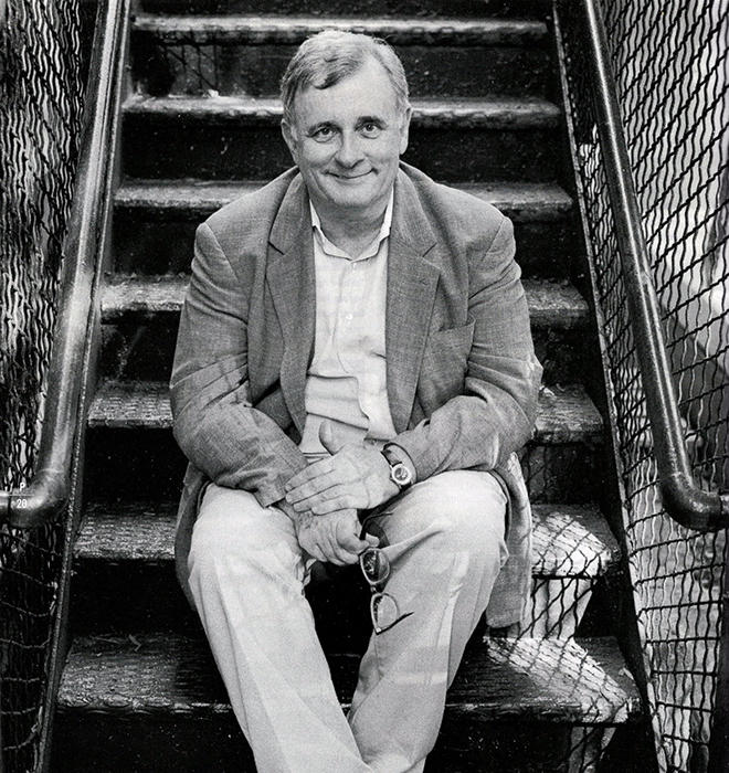 Edmund White sits on a fire escape in this black-and-white photo.