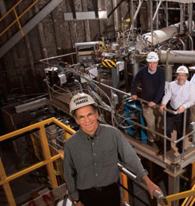 Stewart Prager, foreground, and from left, Richard Hawryluk, Robert Goldston *77, and Masayuki Ono *78 stand in front of the NSTX fusion machine, which is hidden by hardware.