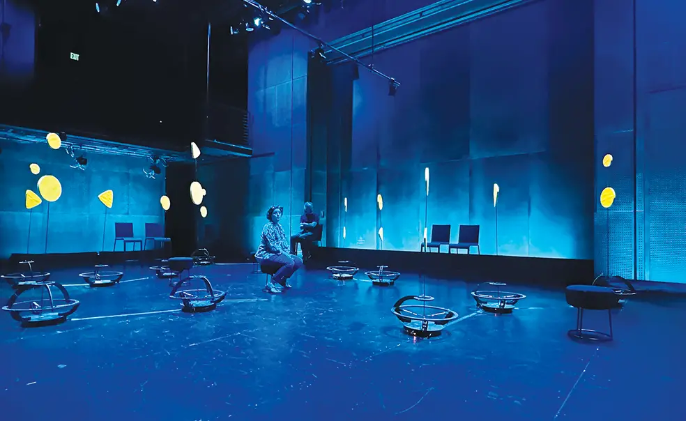 OTC_Rhythm-Bots-10-.jpg Robots scatter around a room lit with blue light.
