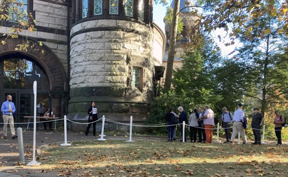 Faculty members standing in line outside a doorway