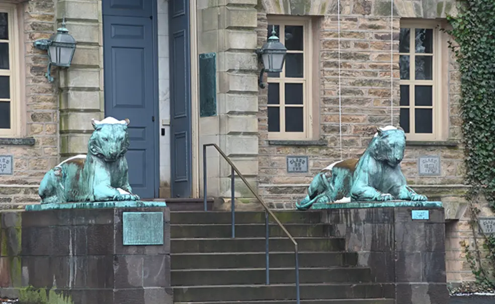20230307_Campus_Snow_MP_4760.jpg Two bronze tiger statues flank a door on a stone building, Princeton’s Nassau Hall.