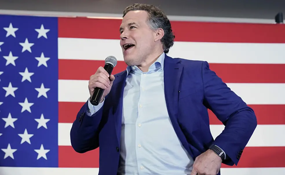 AP_22154784021647.jpg This is a photo of David McCormick speaking into a microphone, with a large American flag in the background.