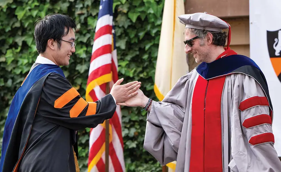 OTC_GradHooding_3220.jpg Yifan Zhang *22, left, receives a high five from chemistry professor Mohammad Seyedsayamdost