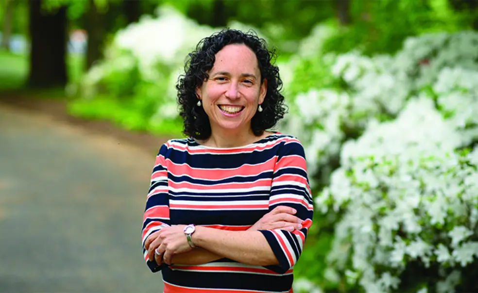 OTC_Rabbi Julie.jpg This is a photo of Rabbi Julie Roth outdoors, with green shrubs in the background.