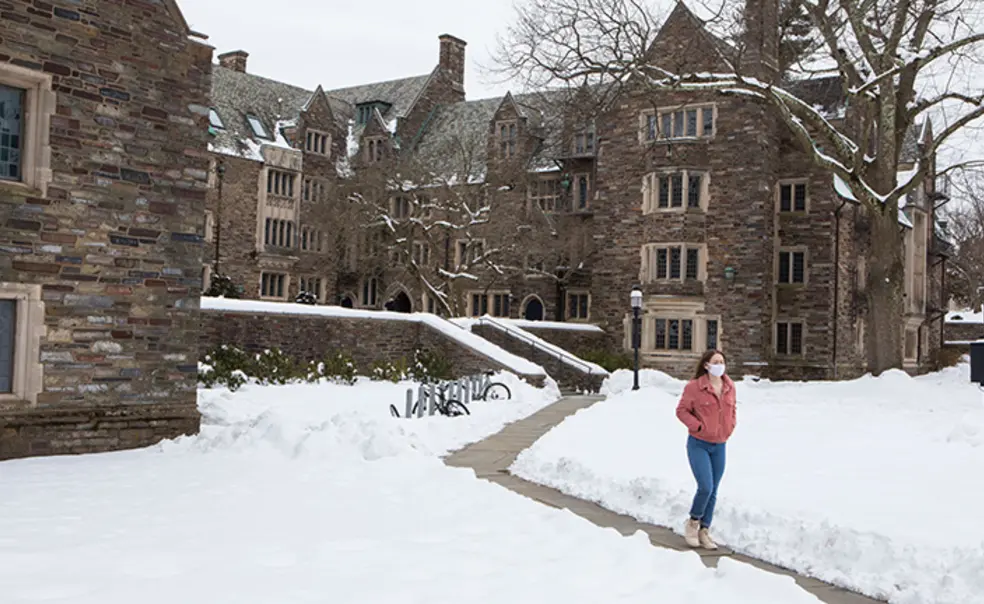 Rally0922_photo.jpg A masked student walks across campus, on a path cut through the snow, in 2021.