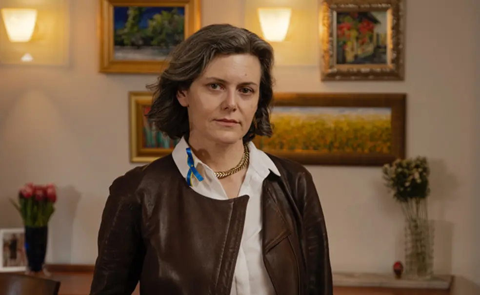 TOW_DoraChomiak.jpg This is a photo of Dora Chomiak ’91 in front of a wall hung with paintings.