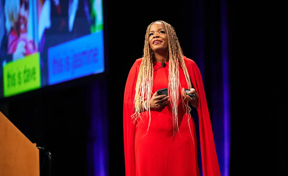 TOW_MichelleSilverthorn.jpg Michelle Silverthorn ’04 speaks on a stage, with a large screen behind her.