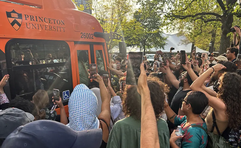 bus-042924.jpg Protesters surrounding a University bus, holding up cell phone cameras