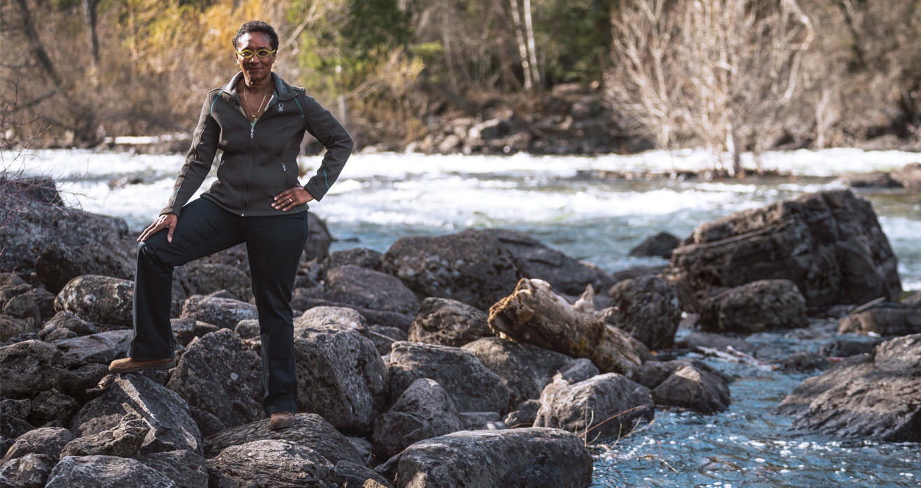 Monica Harris standing on rocks near a swift moving creek in Montana