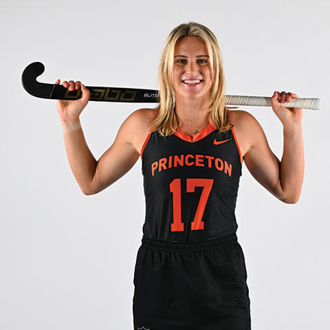 Beth Yeager ’26 holds a field hockey stick across the back of her neck and poses for a photo in her Princeton uniform, #17.